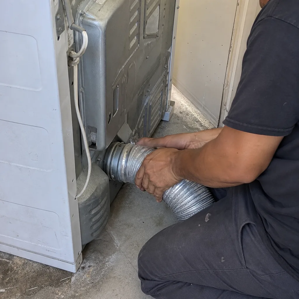 Technician attaching a silver dryer vent hose to a clothes dryer